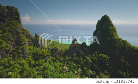 Aerial view majestic mountain cliffs covered in lush green rainforest hills slopes, overlooking pristine turquoise water lagoon, tropical ocean paradise. Popular travel destination, remote wild nature 131815743