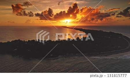 Fakarava Atoll: bright sunset illuminate South Pacific Ocean with sailboats inside the island lagoon silhouette and dramatic orange clouds during golden hour in French Polynesia. Aerial drone 131815777
