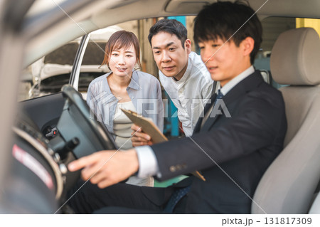 自動車購入・査定・買取にきた夫婦と接客するセールスマンの若いアジア人男性 自動車購入・査定・買取にきた夫婦と接客するセールスマンの若いアジア人男性 131817309