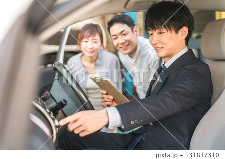 自動車購入・査定・買取にきた夫婦と接客するセールスマンの若いアジア人男性 自動車購入・査定・買取にきた夫婦と接客するセールスマンの若いアジア人男性 131817310
