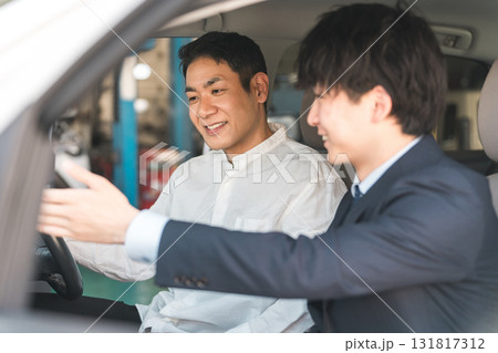 ショールームで自動車の車内で営業マンの説明を受ける顧客の男性 ショールームで自動車の車内で営業マンの説明を受ける顧客の男性 131817312