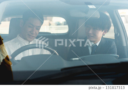 ショールームで自動車の車内で営業マンの説明を受ける顧客の男性 ショールームで自動車の車内で営業マンの説明を受ける顧客の男性 131817313