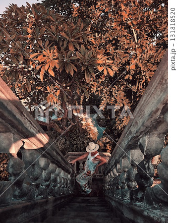 Woman descending steep stone stairs framed by dense orange foliage 131818520