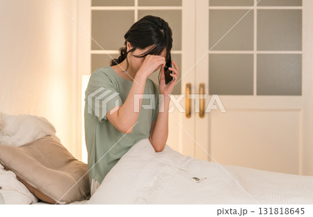 夜ベッドルームで体調不良の電話をする若いアジア人女性 夜ベッドルームで体調不良の電話をする若いアジア人女性 131818645