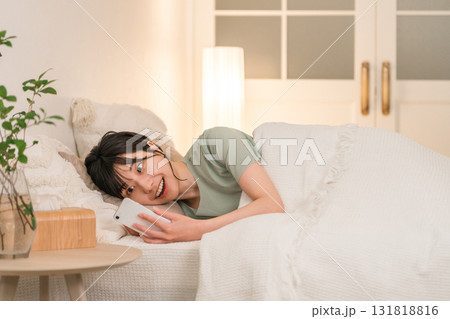 夜ベッドに入りスマホを見る若いアジア人女性 131818816