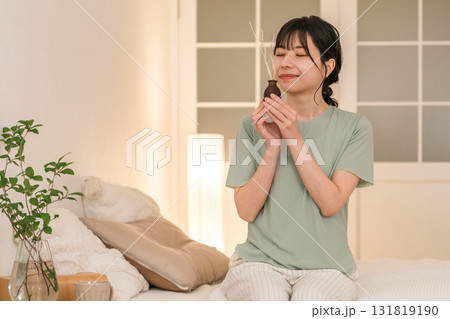 寝室でルームフレグランスの匂いを嗅ぐ若いアジア人女性 131819190