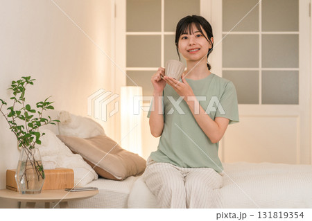 夜の寝室でホットドリンクを飲む若いアジア人女性 夜の寝室でホットドリンクを飲む若いアジア人女性 131819354