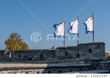 White and blue flag, at Suwon Hwaseong Fortress Wall, with the park view during autumn. The wall is surrounding the center of Suwon, the provincial capital of Gyeonggi-do, in South Korea White and blue flag, at Suwon Hwaseong Fortress Wall, with the park view during autumn. The wall is surrounding the center of Suwon, the provincial capital of Gyeonggi-do, in South Korea 131821597