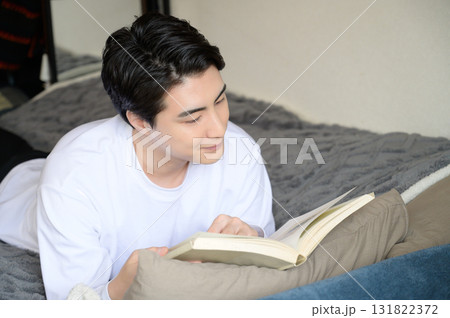ベッドにうつ伏せで本を読む男性 ベッドにうつ伏せで本を読む男性 131822372