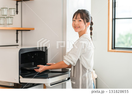 自宅のキッチンでオーブンのトレーを持つ小学生,中学生の女の子(お菓子作り) 自宅のキッチンでオーブンのトレーを持つ小学生,中学生の女の子(お菓子作り) 131828655
