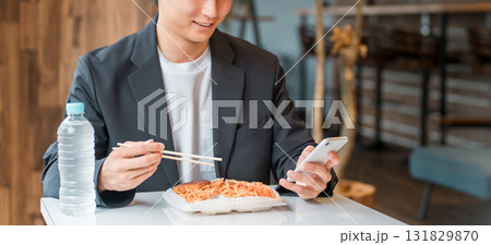 食堂・カフェでランチを食べながらスマホを見るビジネスマン・男性 131829870