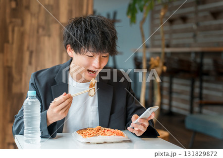 食堂・カフェでランチを食べながらスマホを見るビジネスマン・男性 131829872