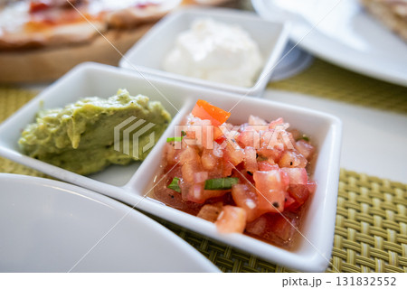 Fresh guacamole and salsa platter local restaurant food vibrant setting close-up culinary experience Fresh guacamole and salsa platter local restaurant food vibrant setting close-up culinary experience 131832552