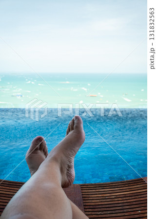 Relaxing feet by infinity pool overlooking ocean luxury resort calm atmosphere serene view Relaxing feet by infinity pool overlooking ocean luxury resort calm atmosphere serene view 131832563
