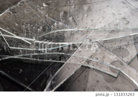 wet glass lies on a black slate board with an uneven texture, pieces of broken transparent glass used in construction covered with water droplets wet glass lies on a black slate board with an uneven texture, pieces of broken transparent glass used in construction covered with water droplets 131833263
