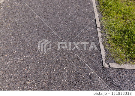 a narrow walking path in the park made of finely crushed rubble, not a wide path for pedestrians to walk in the park in sunny weather 131833338