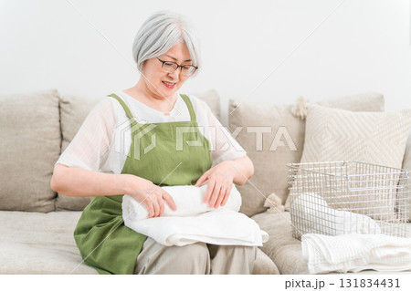 自宅のリビングで洗濯物を畳むシニアのアジア人女性（家事,主婦,専業主婦） 131834431