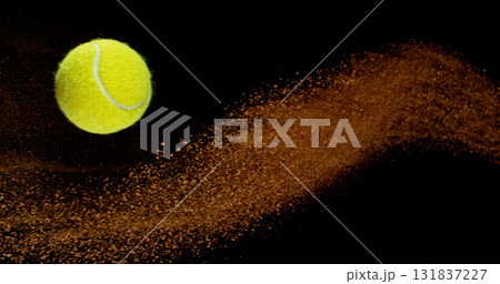 Freeze motion shot of a yellow tennis ball flying through the air, followed by a dynamic trail of clay dust. Freeze motion shot of a yellow tennis ball flying through the air, followed by a dynamic trail of clay dust. 131837227