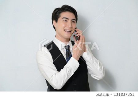 スマホで通話をするベストを着た男性 131837353