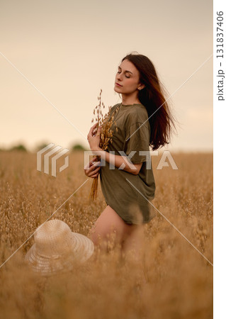 Woman in a field holding wheat and oats while enjoying a serene moment outdoors Woman in a field holding wheat and oats while enjoying a serene moment outdoors 131837406
