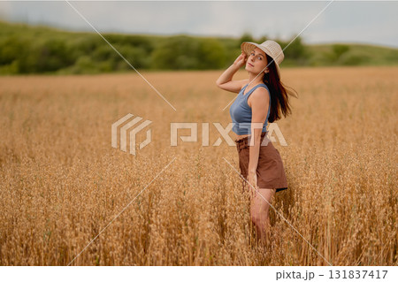 Model poses in a golden field of oats and wheat on a sunny day 131837417