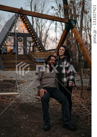 Couple enjoys a cozy moment on a swing in a rustic outdoor setting at dusk Couple enjoys a cozy moment on a swing in a rustic outdoor setting at dusk 131837421