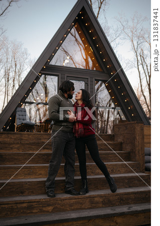 Couple enjoying a romantic moment in front of a cozy mountain cabin at sunset Couple enjoying a romantic moment in front of a cozy mountain cabin at sunset 131837441