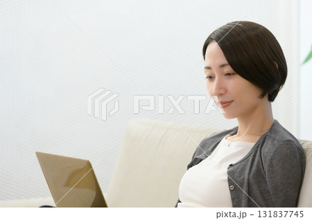 ソファに座ってパソコンで仕事をする女性 131837745