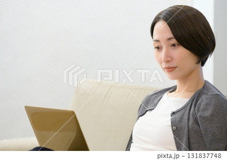 ソファに座ってパソコンで仕事をする女性 131837748