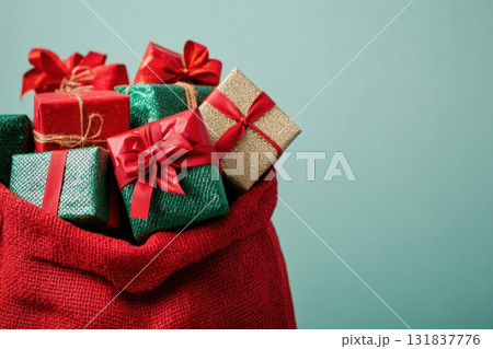 Red gift bag overflowing with colorful wrapped boxes in red and green shades. Minimalist white background, festive ribbons, perfect for Christmas, New Year, and holiday advertising design. Copy space Red gift bag overflowing with colorful wrapped boxes in red and green shades. Minimalist white background, festive ribbons, perfect for Christmas, New Year, and holiday advertising design. Copy space 131837776