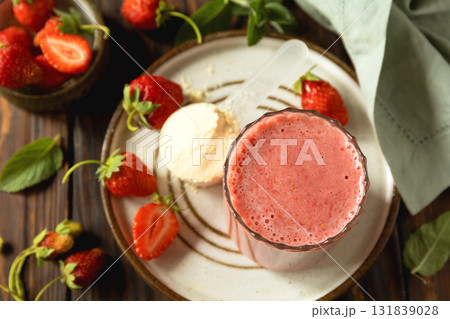 Fresh strawberry protein smoothie on a wooden table with fresh strawberries and a protein powder. 131839028