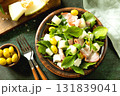 Fresh arugula salad with prosciutto, melon, and olives for a delicious summer meal. 131839041