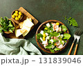 Fresh arugula salad with prosciutto, melon, and olives for a delicious summer meal. Top view flat lay background. Copy space. 131839046