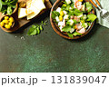 Fresh arugula salad with prosciutto, melon, and olives for a delicious summer meal. Top view flat lay background. Copy space. 131839047