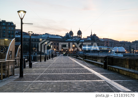 朝焼けの中のサンセバスチャンのコンチャビーチ脇の石畳の歩道と街燈の灯る街並み 131839170