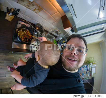 Father Cooking with Baby in Carrier Father Cooking with Baby in Carrier 131841068