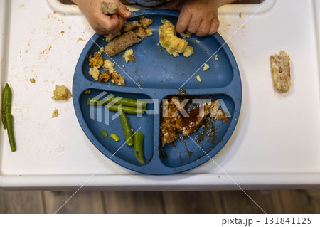 Child Eating Messy Meal on High Chair 131841125