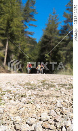 Cyclists riding mountain bikes on gravel road in forest Cyclists riding mountain bikes on gravel road in forest 131841170