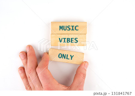 A hand places a wooden block, with the word only on it, beneath two other blocks. The upper blocks say music vibes. The setup is on a white Surface A hand places a wooden block, with the word only on it, beneath two other blocks. The upper blocks say music vibes. The setup is on a white Surface 131841767