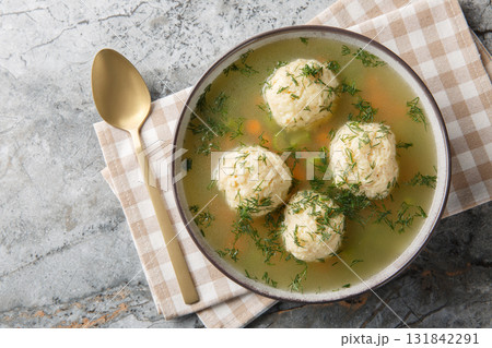 Matzoh Ball Soup soup in a rich chicken broth with the addition of carrot, dill and celery closeup on the plate. Horizontal top view 131842291