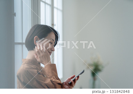 窓際でスマートフォンを操作する女性 窓際でスマートフォンを操作する女性 131842848