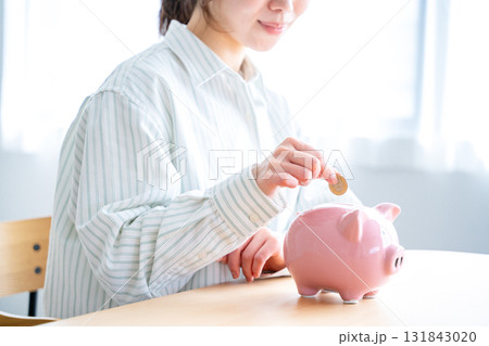 貯金箱にお金を入れる女性 131843020