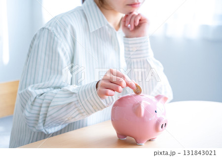 貯金箱にお金を入れる女性 131843021