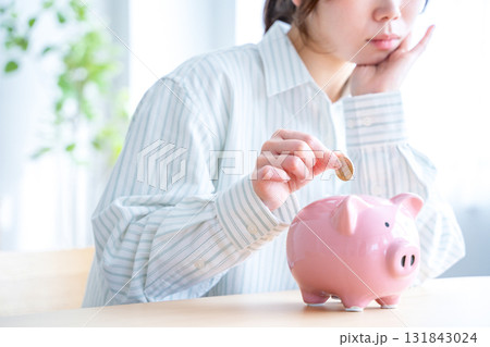 貯金箱にお金を入れる女性 131843024