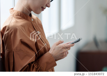 窓際でスマートフォンを操作する女性 窓際でスマートフォンを操作する女性 131843072
