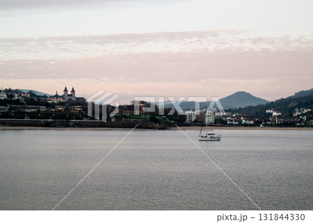 朝焼けの中のサンセバスチャンのコンチャビーチ沿いに並ぶリゾートホテルと街燈と丘の斜面に並ぶ建物 131844330