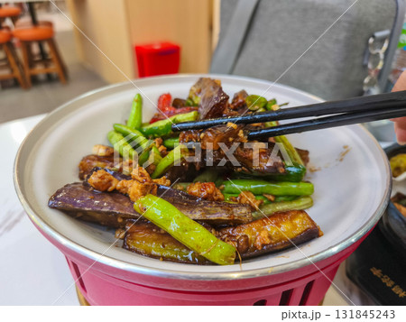 Delicious homemade stir fried eggplant with minced chicken and green beans, a popular Asian dish, served in a white bowl with chopsticks. 131845243