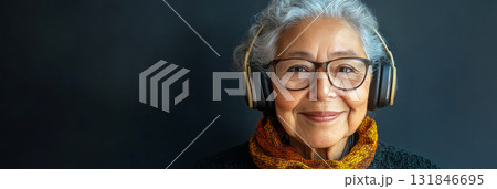 A relaxed, smiling Arab grandma with headphones stands in front of a navy blue background, embodying chic elegance in a simple, minimalist mock-up design, banner 131846695