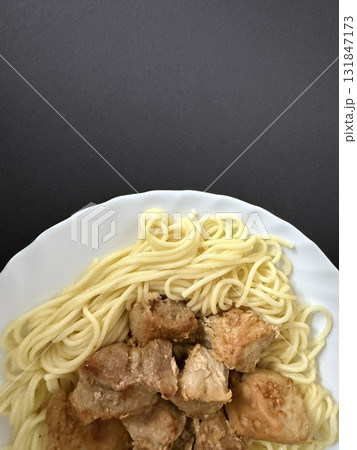 Close-up shot of spaghetti with fried pork pieces on a white plate. Cooking delicious food at home. 131847173