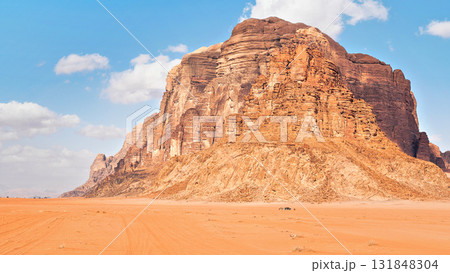 Large mountain in red desert, small 4wd vehicle in foreground for scale - typical scenery of Wadi Rum, Jordan 131848304